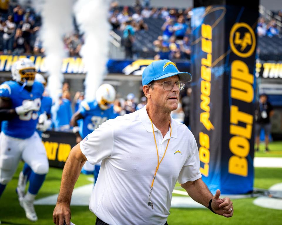 Chargers coach Jim Harbaugh leads his players onto the field for Saturday's exhibition game against the Rams.