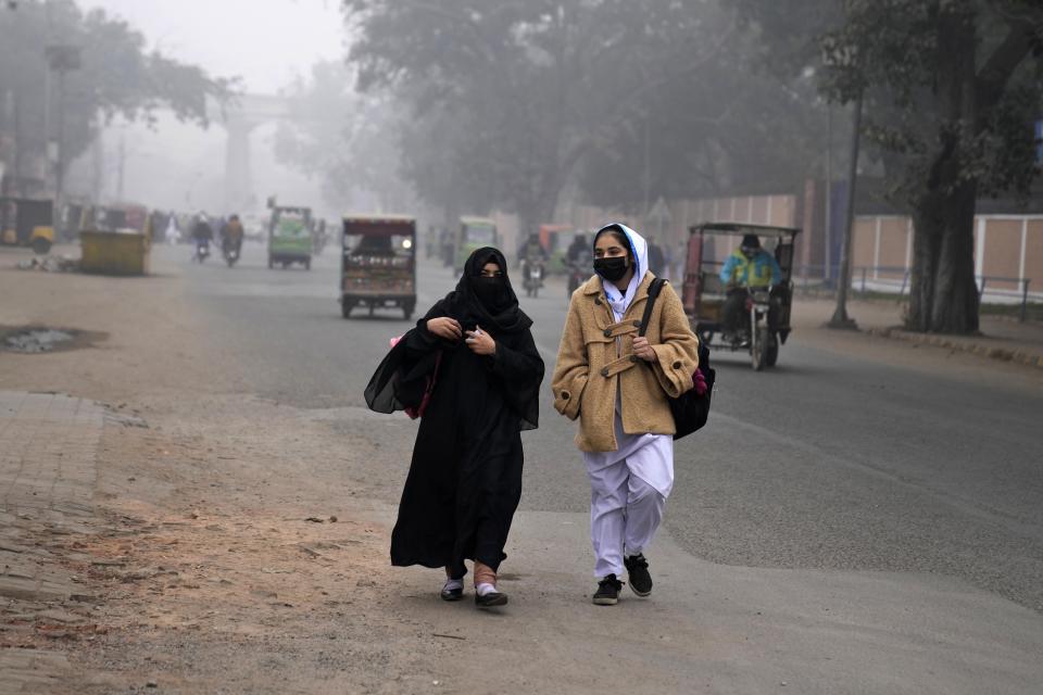 Students, wearing masks, walk toward their college as smog envelops the area, in Lahore, Pakistan, Monday, Jan. 15, 2024. Lahore is in an airshed, an area where pollutants from industry, transportation and other human activities get trapped and cannot disperse easily. (AP Photo/K.M. Chaudary)