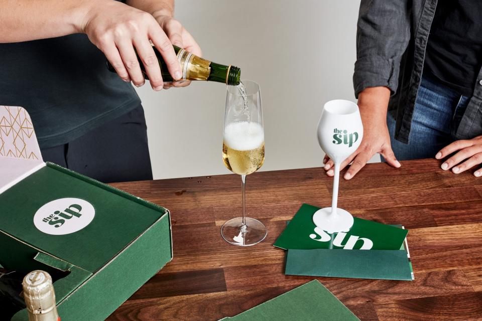 person pouring a mini-bottle of champagne into a glass