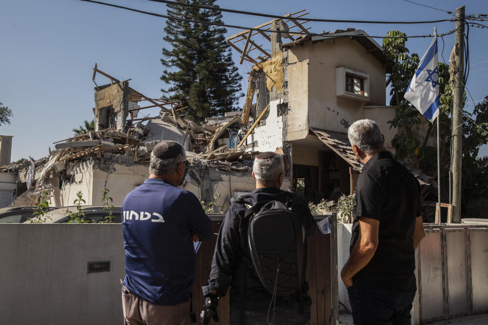 People look at a house after it was hit by a rocket fired from the Gaza Strip, in Yehud, central Israel, Wednesday, May 12, 2021. The house was hit Tuesday as barrage of rockets fired from the Gaza Strip toward central Israel. (AP Photo/Heidi Levine)