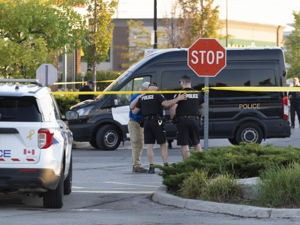 Police officers embrace at the scene of a shooting in Mississauga, Ontario, Monday, Sept. 12, 2022. (Arlyn McAdorey/The Canadian Press via AP)