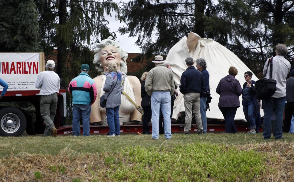 People gather to look at parts of a 26-foot-tall, 34,000-pound statue named "Forever Marilyn" in Hamilton, N.J., Tuesday, April 8, 2014. The sculpture depicting Marilyn Monroe in her memorable billowing skirt pose from the "The Seven Year Itch" is part of an exhibit at the Grounds for Sculpture in Hamilton, honoring its designer, Seward Johnson. (AP Photo/Mel Evans)