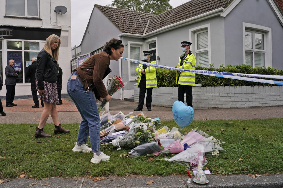 A woman places a floral tribute on the road leading to the Belfairs Methodist Church in Eastwood Road North, in Leigh-on-Sea, Essex, England, Saturday, Oct. 16, 2021. David Amess, a long-serving member of Parliament was stabbed to death during a meeting with constituents at a church in Leigh-on-Sea on Friday, in what police said was a terrorist incident. A 25-year-old man was arrested in connection with the attack, which united Britain's fractious politicians in shock and sorrow. (AP Photo/Alberto Pezzali)