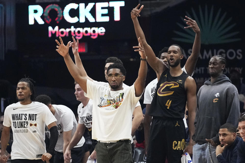 Cleveland Cavaliers' Donovan Mitchell, center, and Evan Mobley (4) cheer in the bench area in the first half of an NBA basketball game against the New York Knicks, Sunday, March 3, 2024, in Cleveland. (AP Photo/Sue Ogrocki)