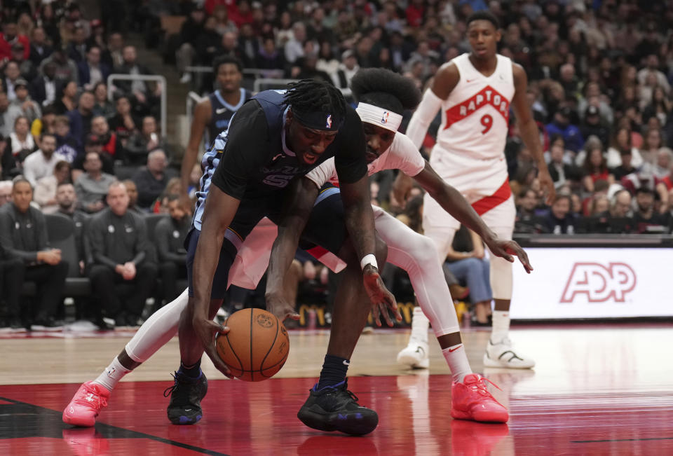 Memphis Grizzlies guard Vince Williams Jr. (5) and Toronto Raptors forward Chris Boucher, center, battle for the ball during the first half of an NBA basketball game in Toronto, Monday Jan. 22, 2024. (Nathan Denette/The Canadian Press via AP)