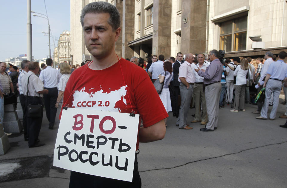 A Communist supporter pickets parliament headquarters with a poster reading: "WTO is Death for Russia" in Moscow, Russia, Tuesday, July 10, 2012. Russia's parliament is due to ratify an agreement for Russia to join the World Trade Organization in a move that will push Moscow to open up its economy. (AP Photo/Misha Japaridze)