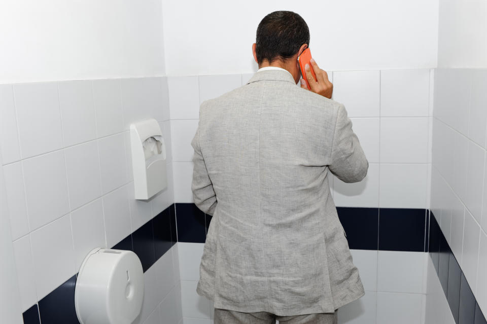 A person on the phone using a bathroom