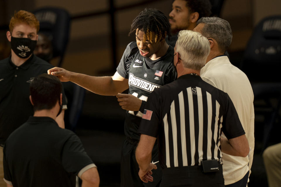 Providence's Brycen Goodine, center, reacts to the stream of sunlight as Villanova's head coach Jay Wright, right, looks on with the official as it causes a delay in the start of the second half of an NCAA college basketball game Saturday, Jan. 23, 2021, in Villanova, Pa. Villanova won 71-56. (AP Photo/Chris Szagola)