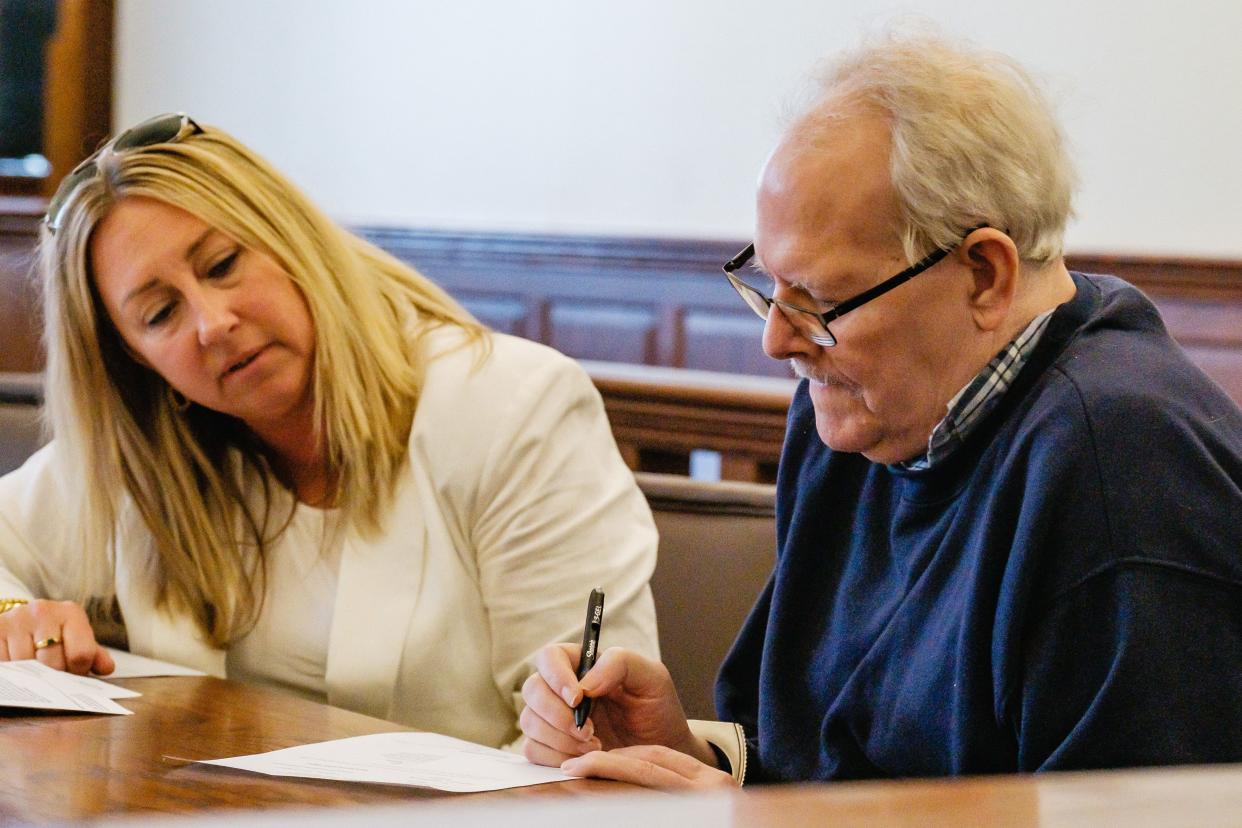 Donald E. Whiting Jr. signs a document Monday waiving his right to a jury trial for attempted murder as Public Defender Nicole Stephen looks in Tuscarawas County Common Pleas Court. He was deemed not guilty by reason of insanity for firing shots at county sheriff's deputies during a 2021 confrontation.