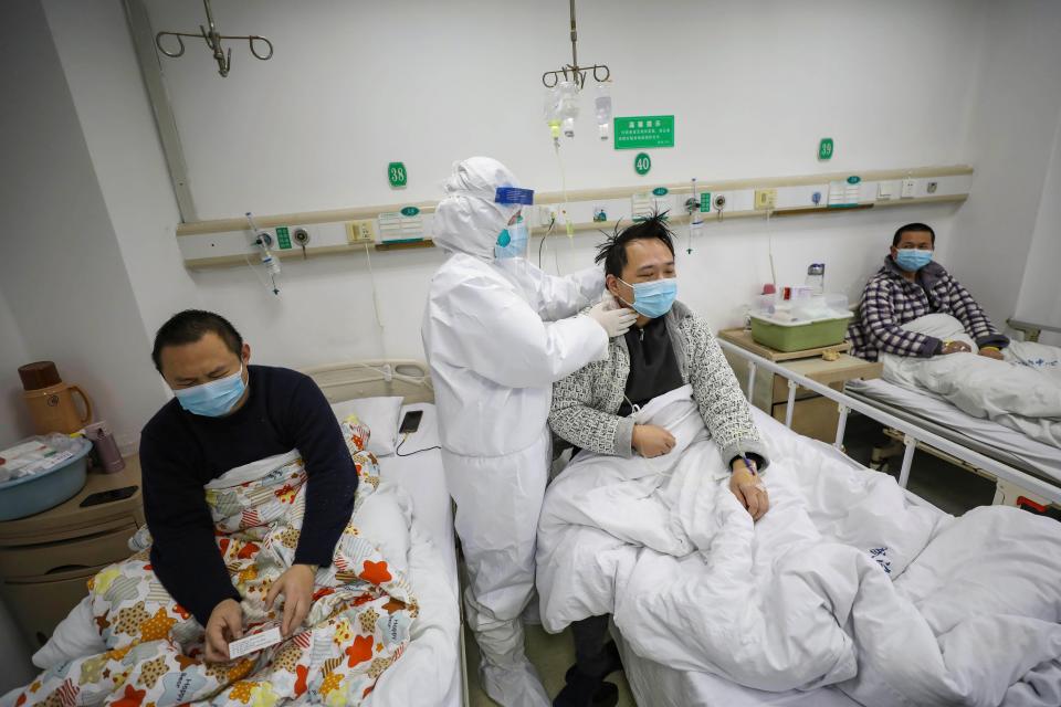 A doctor checks the conditions of a patient in Jinyintan Hospital, designated for critical COVID-19 patients, in Wuhan in central China's Hubei province Thursday, Feb. 13, 2020. China on Thursday reported 254 new deaths and a spike in virus cases of 15,152, after the hardest-hit province of Hubei applied a new classification system that broadens the scope of diagnoses for the outbreak, which has spread to more than 20 countries. (Chinatopix Via AP)