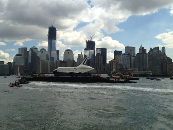 Space shuttle Enterprise sails up NYC's Hudson Rover with the World Trade Center's Freedom Tower in the background while traveling to the Intrepid Sea, Air and Space Museum on June 6, 2012.