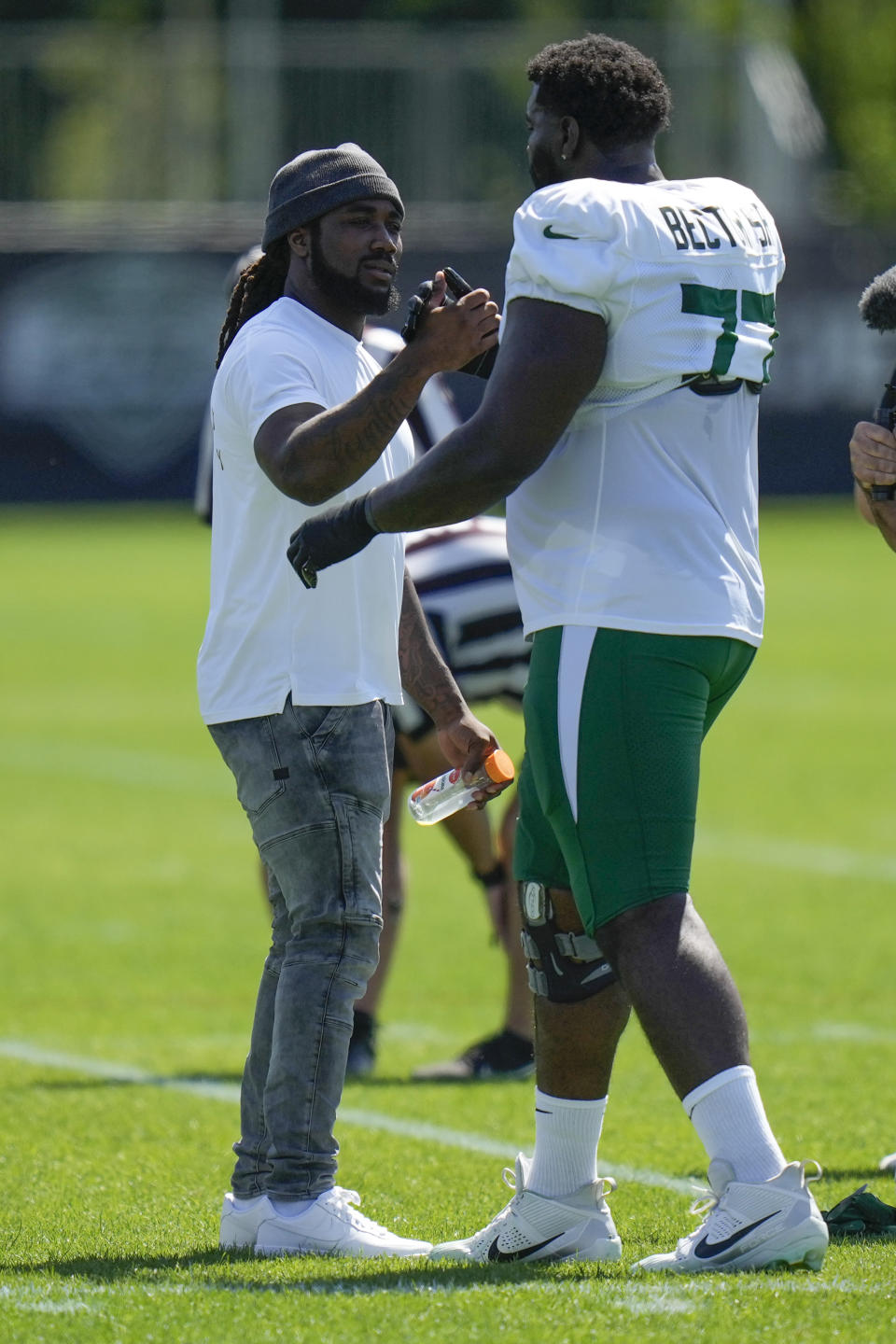 Running back Dalvin Cook, left, greets New York Jets' Mekhi Becton as he watches a New York Jets practice session at the NFL football team's training facility in Florham Park, N.J., Sunday, July 30, 2023. (AP Photo/Seth Wenig)