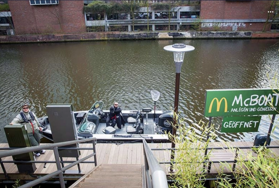 Someone on a boat is pulled up to a dock by McDonald's and ordering food