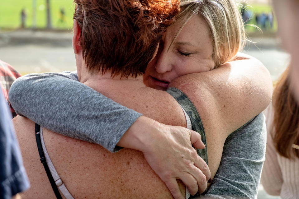 Christine Heffernan embraces her friend while waiting for her son, Alex Cox, 17, a student at Saugus High School, to arrive to the reunification center. | Hilary Swift