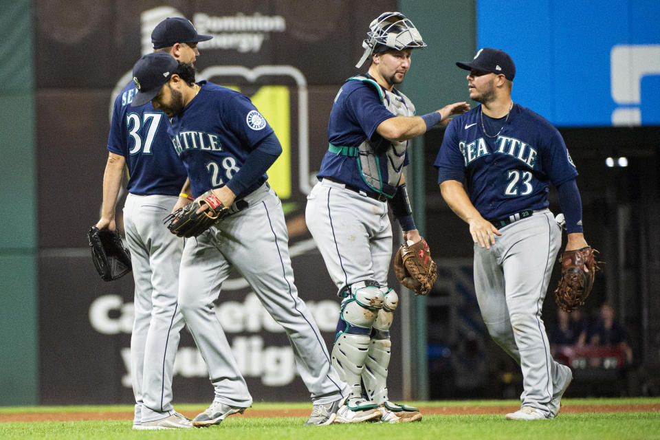 Seattle Mariners catcher Cal Raleigh congratulates Ty France (23) as Eugenio Suarez (28) runs off the field after the team's 4-0 win over the Cleveland Guardians in a baseball game in Cleveland, Saturday, Sept. 3, 2022. (AP Photo/Phil Long)