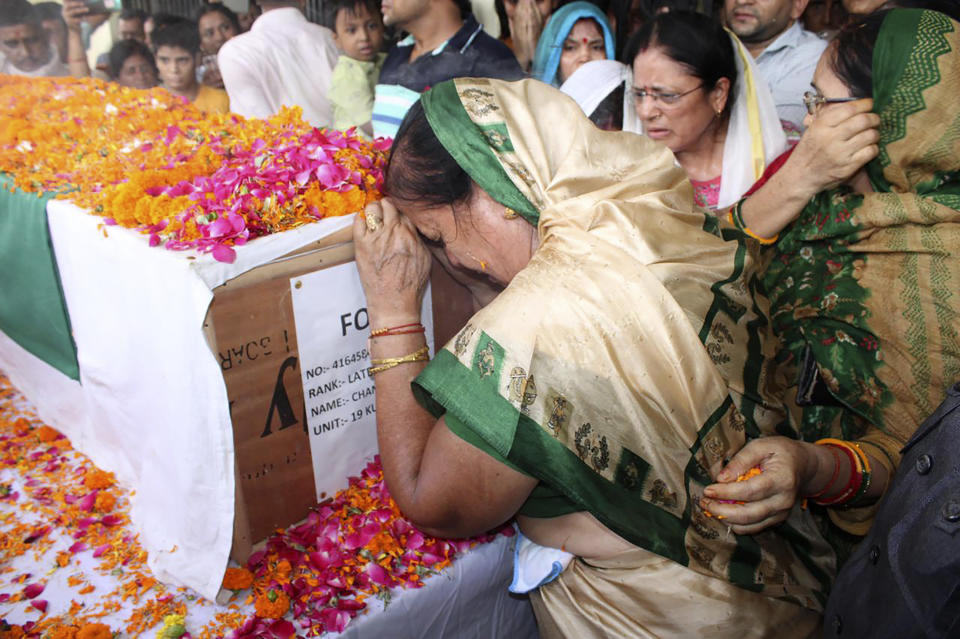 In this photo provided by the Indian Army, a woman cries by the coffin containing the remains of Chandra Shekhar, an Indian army soldier found more than 38 years after he went missing, in Haldwani, India, Wednesday, Aug. 17, 2022. The soldier and 17 other colleagues were occupying a ridge on Siachen Glacier, high in the Karakoram range in disputed Kashmir's Ladakh region, in May 1984 when they were hit by an avalanche, officials said. (Indian Army via AP)