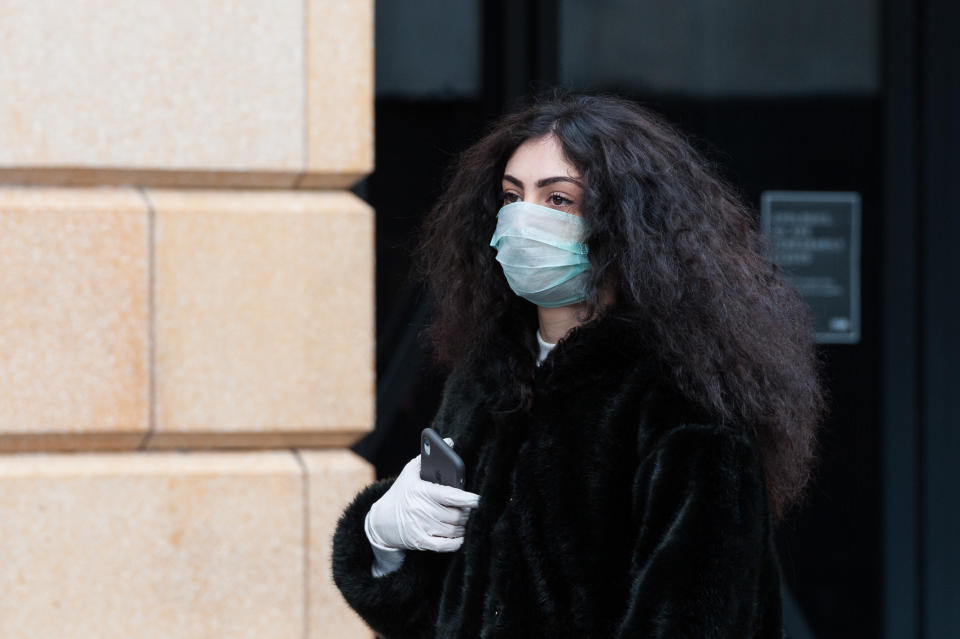 A young woman wears a protective face mask walks in Leicester Square in central London as the coronavirus pandemic continues.