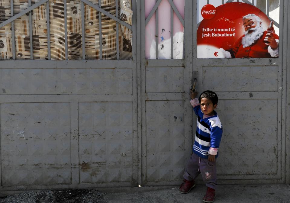 A Roma child stands in front of a shelter bearing an image of Santa Claus as advertised by Coca-Cola — which is largely credited with popularizing the modern-day image of him as a jolly white man, seen all over the world. (Photo: ARMEND NIMANI/AFP via Getty Images)