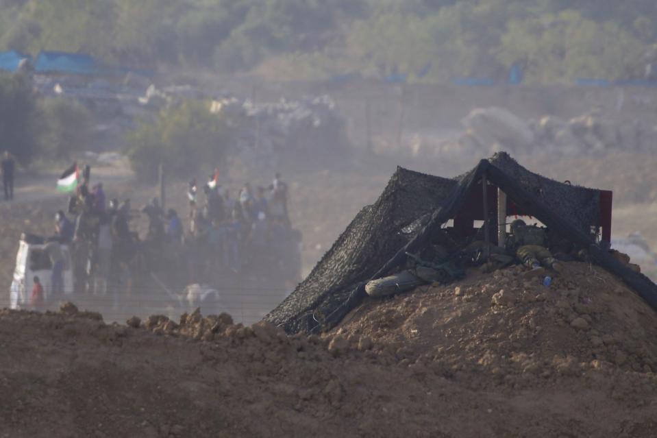 Israeli soldiers lay prone at their position overlooking a Palestinian protest at Israel and Gaza border, Israel, Friday, Oct. 5, 2018. The Israeli military said Thursday it was bolstering its forces along the Gaza border ahead of another expected explosive Hamas-orchestrated protest. (AP Photo/Ariel Schalit)