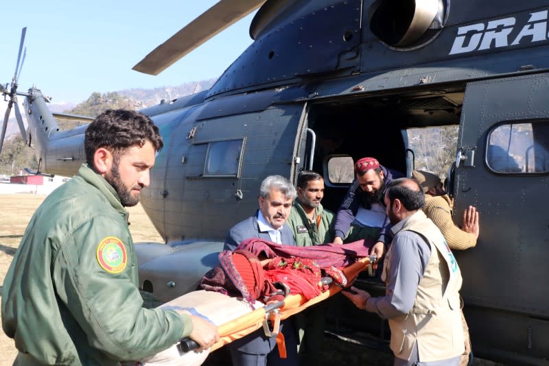 People transport an injured woman, who was rescued after heavy snowfall and avalanches in Neelum Valley near line of control (LoC), from a helicopter to a hospital in Muzaffarabad