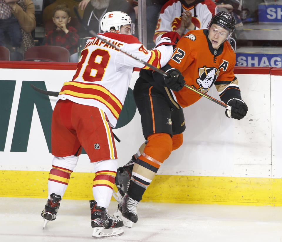 Anaheim Ducks' Josh Manson, right, takes a hit from Calgary Flames' Andrew Mangiapane during second period NHL hockey action in Calgary, Alberta, Monday, Feb. 17, 2020. (Larry MacDougal/The Canadian Press via AP)