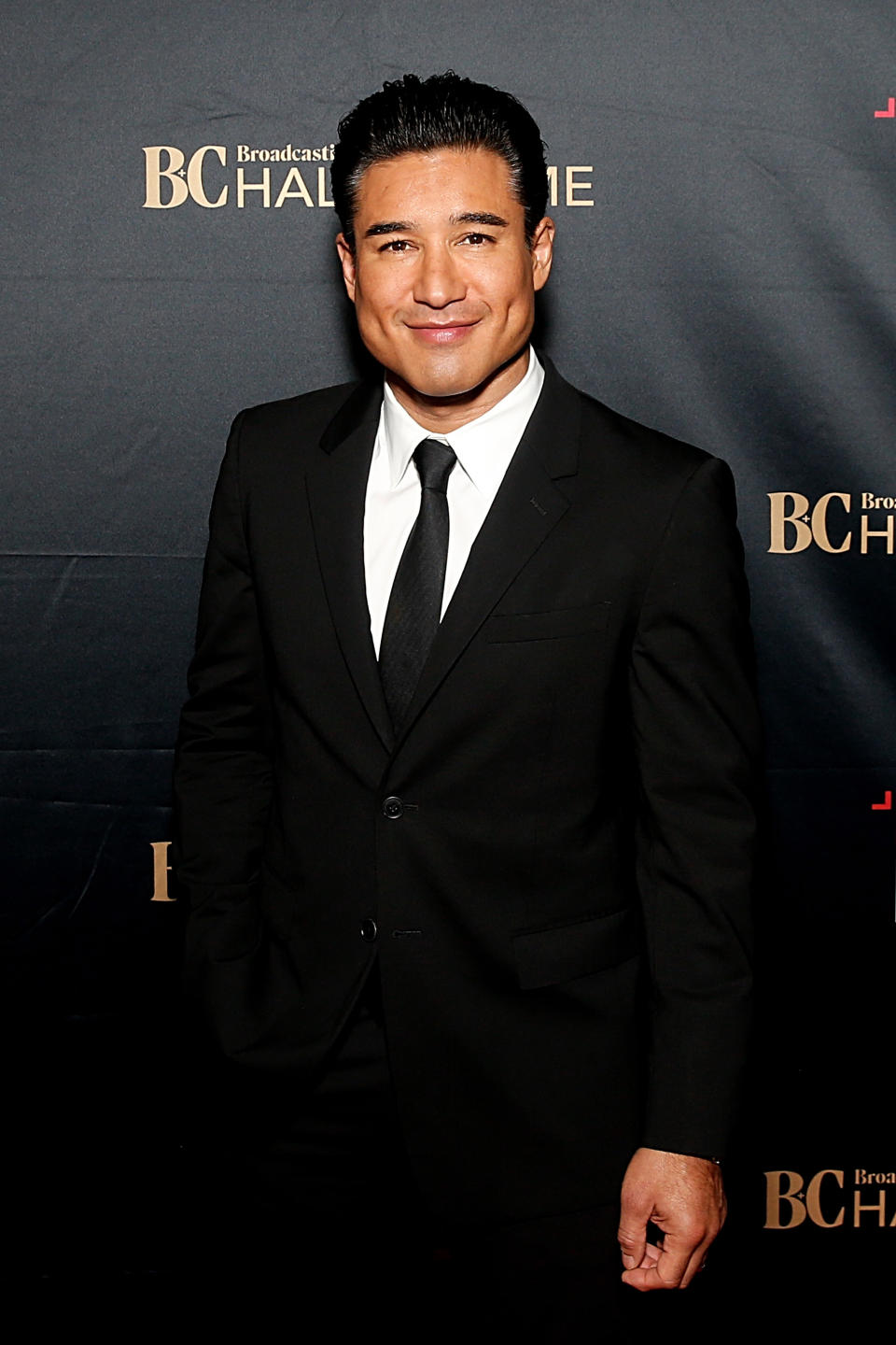 Man in a suit at Broadcast Hall of Fame event; red carpet setting