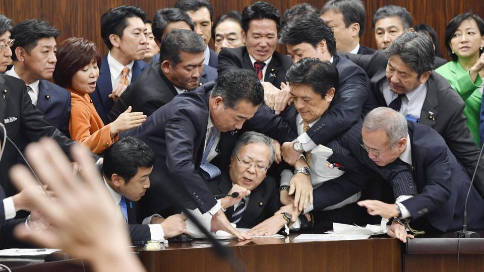 Handgemenge im japanischen Parlament: Mitglieder der Regierungspartei und der Opposition kämpfen in der Zuwanderungsdebatte um ein Mikrofon. Foto: Yoshitaka Sugawara/Kyodo News/AP