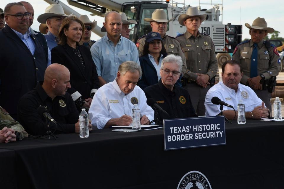 Gov. Greg Abbott signs three bills into law at a border wall construction site in Brownsville, Texas on 18 December that aims to deter illegal immigration (AP)