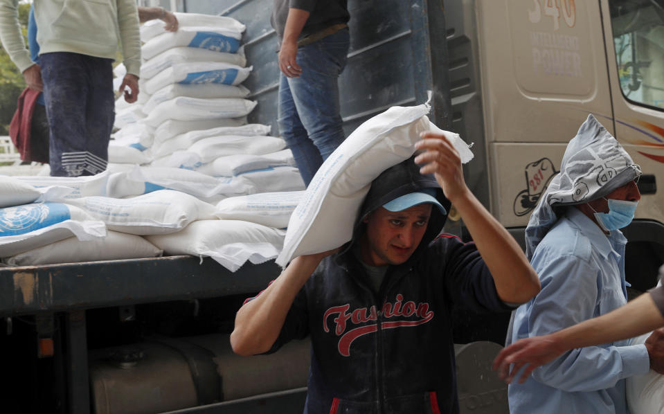Palestinian workers unloads sacks of flour distributed by the United Nations Relief and Works Agency (UNRWA) for poor refugee families, at the Sheikh Redwan neighborhood of Gaza City, Tuesday, March 31, 2020. The United Nations has resumed food deliveries to thousands of impoverished families in the Gaza Strip after a three-week delay caused by fears of the coronavirus. UNRWA, provides staples like flour, rice, oil and canned foods to roughly half of Gaza’s 2 million people. (AP Photo/Adel Hana)