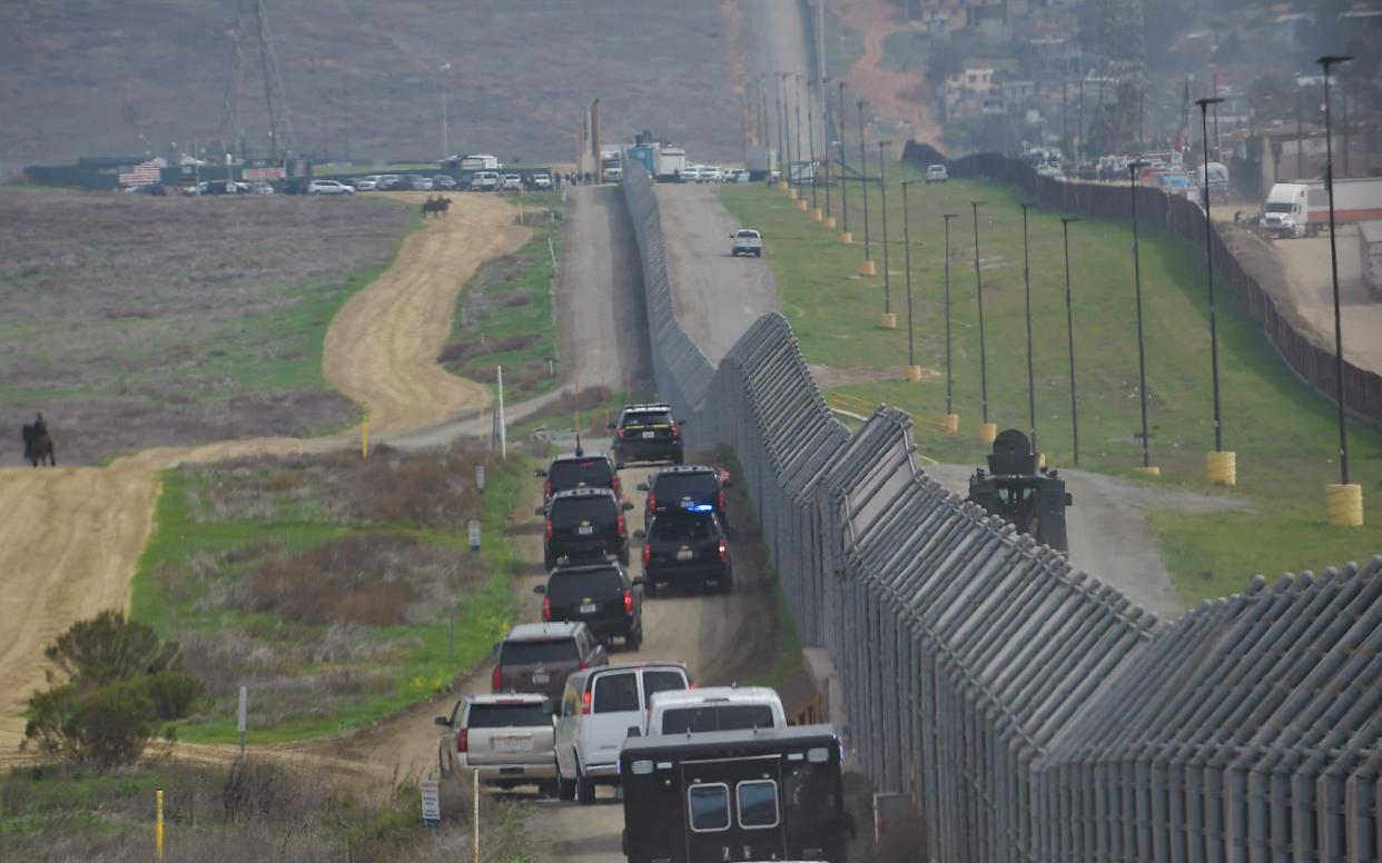 Motorcade carrying US President Donald Trump drives past a US-Mexico border fence on March 13 - AFP