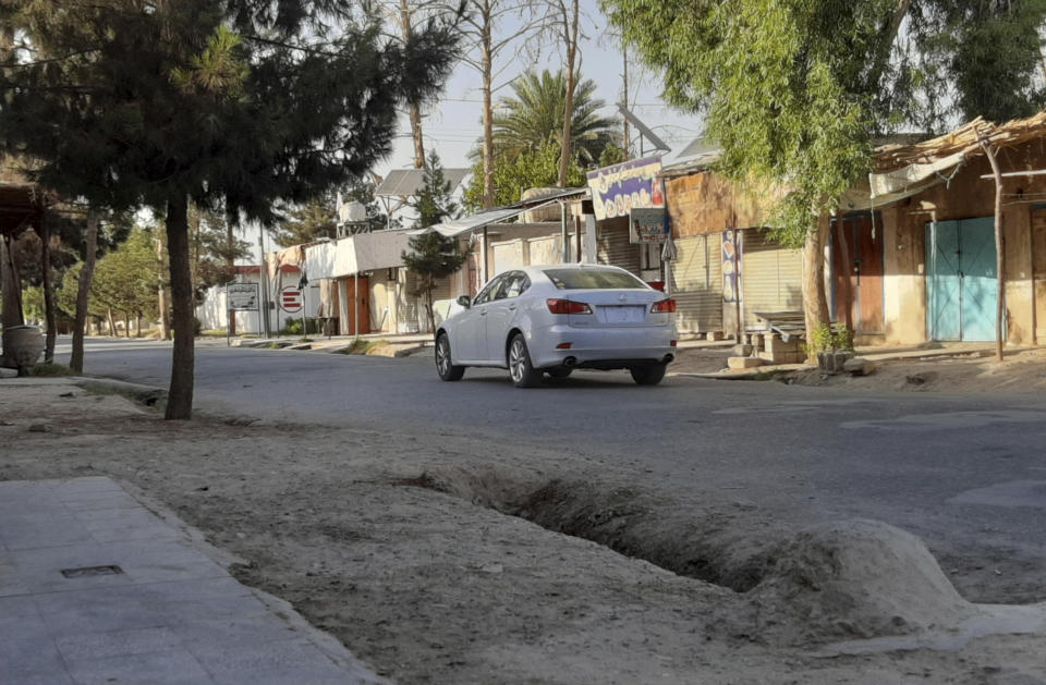 A lone car drives in a deserted street lined with shuttered shops during fighting between Taliban and Afghan security forces, in Lashkar Gah, Helmand province, southern Afghanistan, Tuesday, Aug. 3, 2021. U.S. and Afghan airstrikes were hitting Taliban targets in southern Helmand province on Wednesday, officials said, in an effort to dislodge the insurgents a day after they captured much of the provincial capital of Lashkar Gah. (AP Photo/Abdul Khaliq)