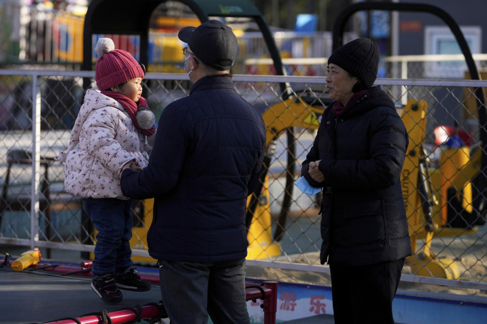 A couple watch a child play on a bouncing bed at an amusement park in Beijing, Monday, Jan. 17, 2022. The number of babies born in China continued to shrink last year in a decade-long trend, official data showed Monday, as a declining workforce adds pressure to the ruling Communist Party's ambitions to boost national wealth and global influence. (AP Photo/Andy Wong)