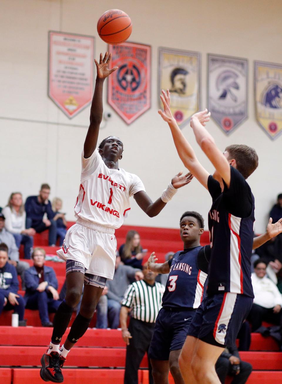 Lansing Everett's Mensi Murkb, left, shoots against East Lansing's Christian Dunn, right, and Dorijan Jackson (3), Tuesday, Dec. 13, 2022, in Lansing.