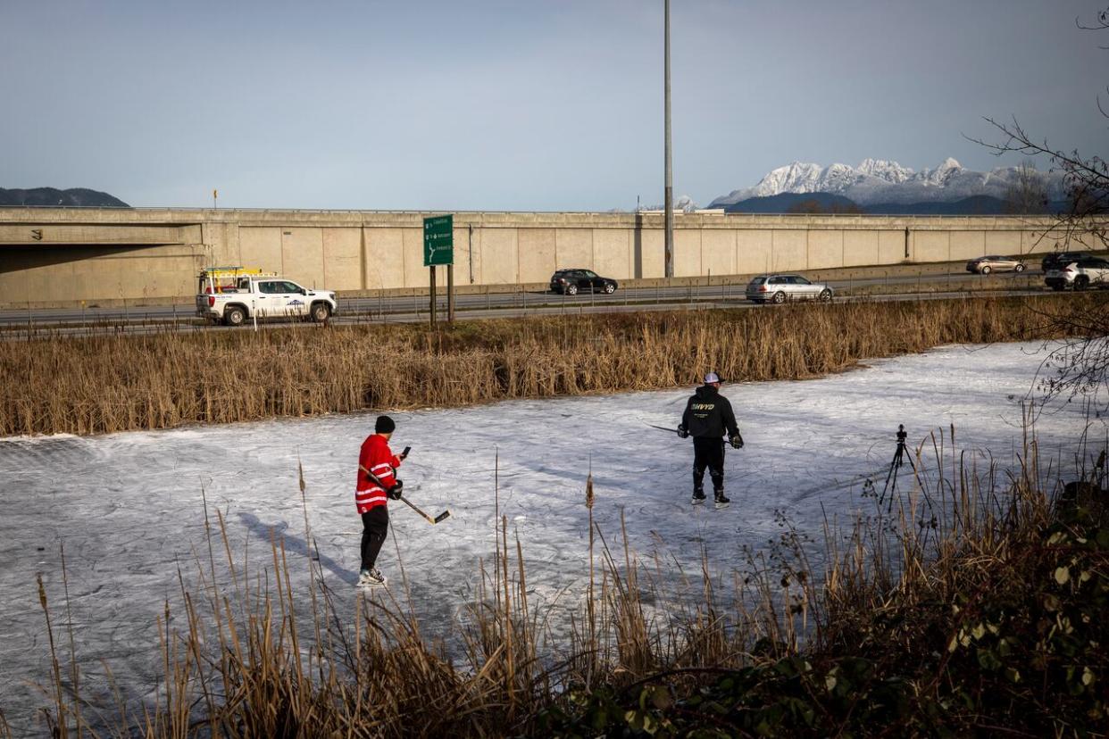 Two people play hockey on a frozen marsh near the Pitt River bridge in Port Coquitlam on Monday. Freezing rain and snow is expected in Metro Vancouver Tuesday night. (Ben Nelms/CBC - image credit)