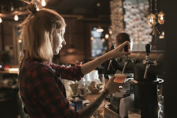 Female bartender pouring beer from tap