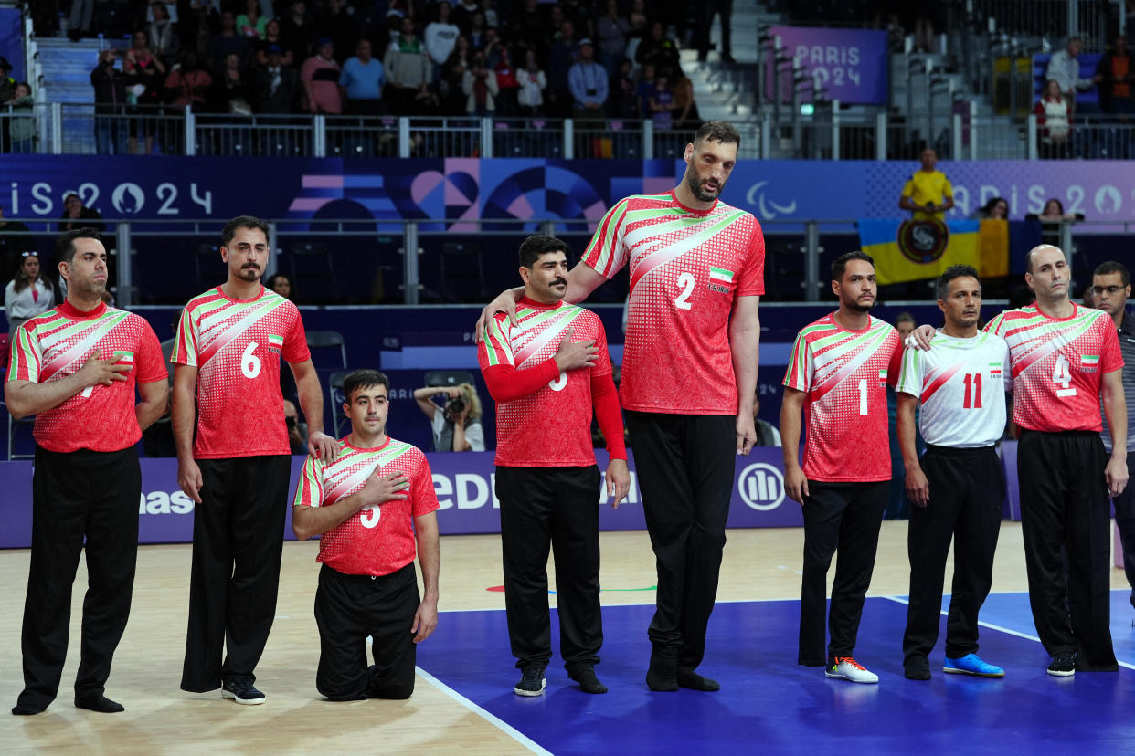 Iran's #2 Morteza Mehrzadselakjani (C) and his teammates listen to their national anthem before the sitting volleyball men's preliminary round pool B match between Iran and Ukraine. / Credit: DIMITAR DILKOFF/AFP via Getty Images