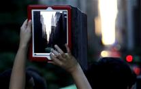 A woman takes a photo with an iPad as people wait for the sun to set through the middle of the buildings on 42nd Street in New York's Manhattan borough during a phenomenon known as Manhattanhenge, Wednesday, July 11, 2012. Manhattanhenge, sometimes referred to as the Manhattan Solstice, happens when the setting sun aligns with the east-to-west streets of the main street grid. The term references Stonehenge, at which the sun aligns with the stones on the solstices in England. (AP Photo/Julio Cortez)