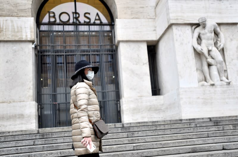 FILE PHOTO: Woman in a face mask is seen in front of the Italian Stock Exchange in Milan