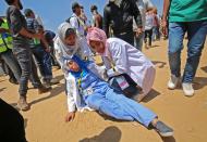 <p>Palestinian woman medics tend to an injured colleague during clashes near the border with Israel, east of Khan Yunis in the southern Gaza Strip on May 15, 2018, amidst protests marking 70th anniversary of Nakba — also known as Day of the Catastrophe in 1948 — and against the US’ relocation of its embassy from Tel Aviv to Jerusalem. (Photo: Said Khatib/AFP/Getty Images) </p>