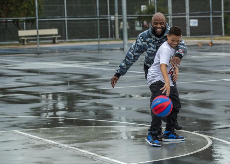 SHERMAN OAKS, CA-NOVEMBER 15, 2023, 2023: Prince Williams, 9, and his father Lamont, 39, play basketball on a wet court due to the rain at Van Nuys/Sherman Oaks Recreation Center in Sherman Oaks. (Mel Melcon / Los Angeles Times)
