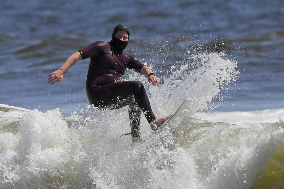 FILE - In this May 13, 2020, file photo, Tim O'Rourke surfs with a face covering to protect him from the coronavirus at Venice Beach, during the coronavirus outbreak in Los Angeles. Masks are required at Los Angeles County beaches, which reopened Wednesday to join counterparts in other states that have allowed a somewhat limited return to famed stretches of sand. (AP Photo/Mark J. Terrill, File)