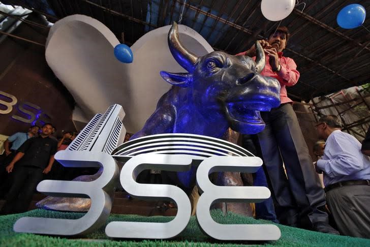 A man ties a balloon to the horns of a bull statue at the entrance of the Bombay Stock Exchange (BSE) while celebrating the Sensex index rising to over 30,000, in Mumbai, India April 26, 2017. REUTERS/Shailesh Andrade/File Photo