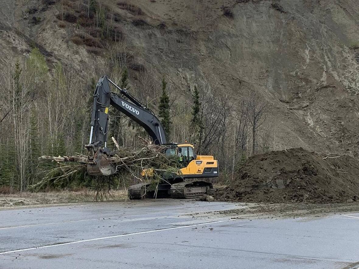An excavator helps clean up the debris from last month's landslide on Robert Service Way in Whitehorse. The city expects to finish the clean up Thursday and begin construction of a 100-metre sheet pile wall Friday. (Submitted by City of Whitehorse - image credit)