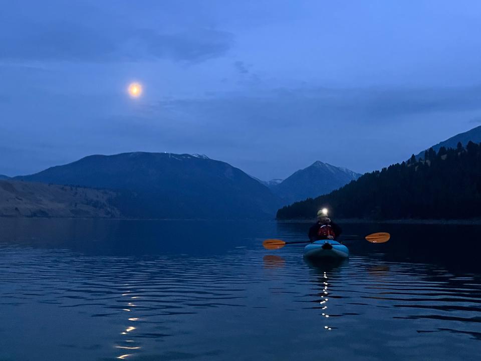 Joshua Shoffner leads a group of nighttime kayakers while the moon shines over Wallowa Lake.