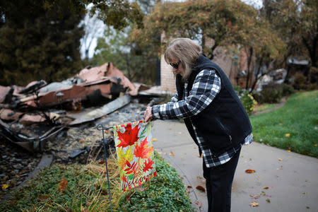 Gerryann Wulbern rehangs a welcome sign she found unburned on her lawn after returning to her home for the first time since the Camp Fire devastated the area in Paradise, California, U.S. November 22, 2018. REUTERS/Elijah Nouvelage/File Photo