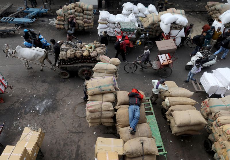 FILE PHOTO: A labourer sleeps on sacks as traffic moves past him in a wholesale market in the old quarters of Delhi