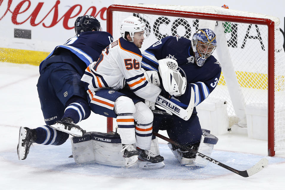 Winnipeg Jets' Pierre-Luc Dubois (13) and Edmonton Oilers' Kailer Yamamoto (56) collide with Jets goaltender Connor Hellebuyck (37) during the third period of an NHL hockey game Wednesday, April 28, 2021, in Winnipeg, Manitoba. (John Woods/The Canadian Press via AP)