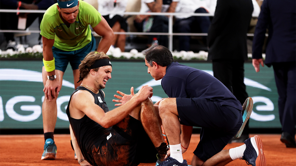 Alexander Zverev (pictured middle) in pain on the ground as he is checked on.