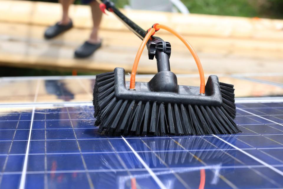 A close up of a brush tool being used to clean solar panels. 