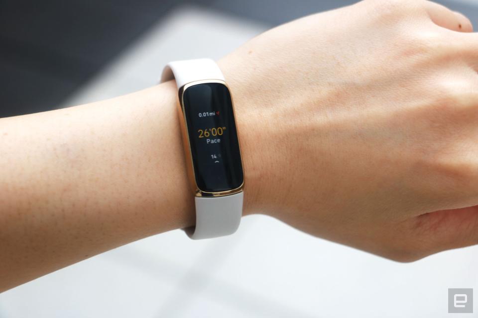 <p>The Fitbit Luxe with a light pink silicone band on a wrist against a concrete gray background. The screen shows a run being tracked with a pace of 26:00 and 0.01 miles traveled.</p>
